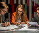 Three business professionals seated at a table, reviewing documents and discussing strategies.