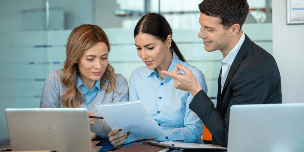 Three business professionals reviewing a document together in a modern office setting.